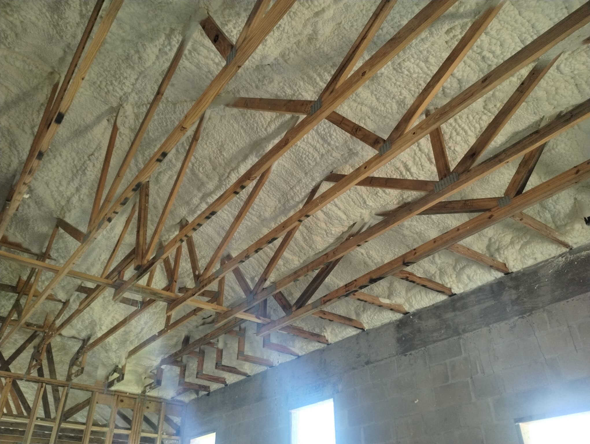 Spray foam insulation beneath a roof deck with exposed wood trusses